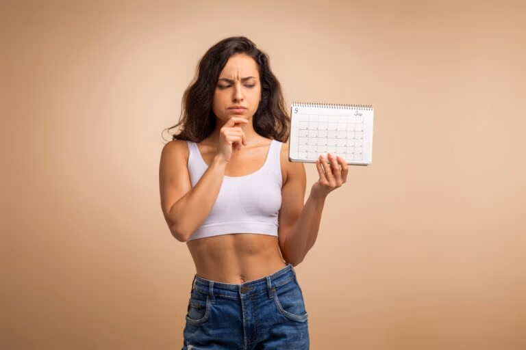 Confused millennial woman with calendar on beige background