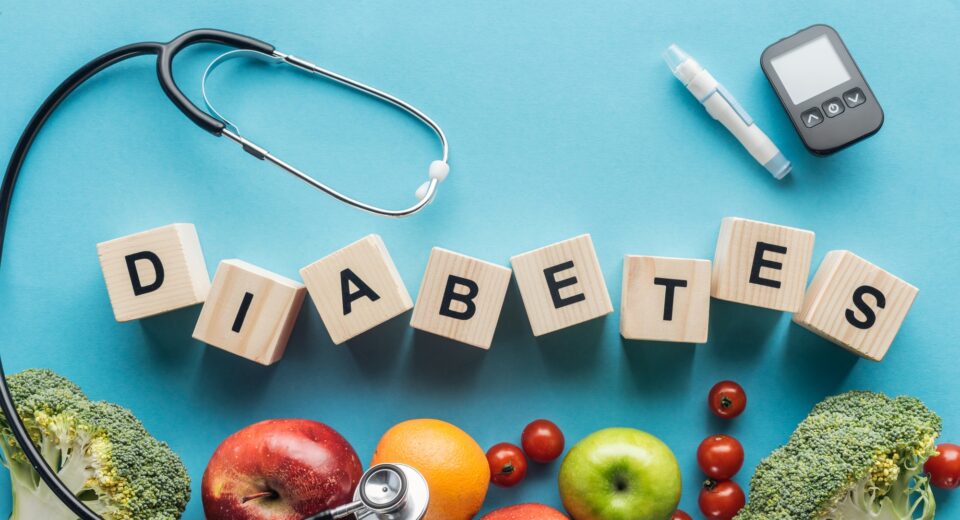 diabetes lettering made of wooden cubes with medical equipment and fruits on blue background