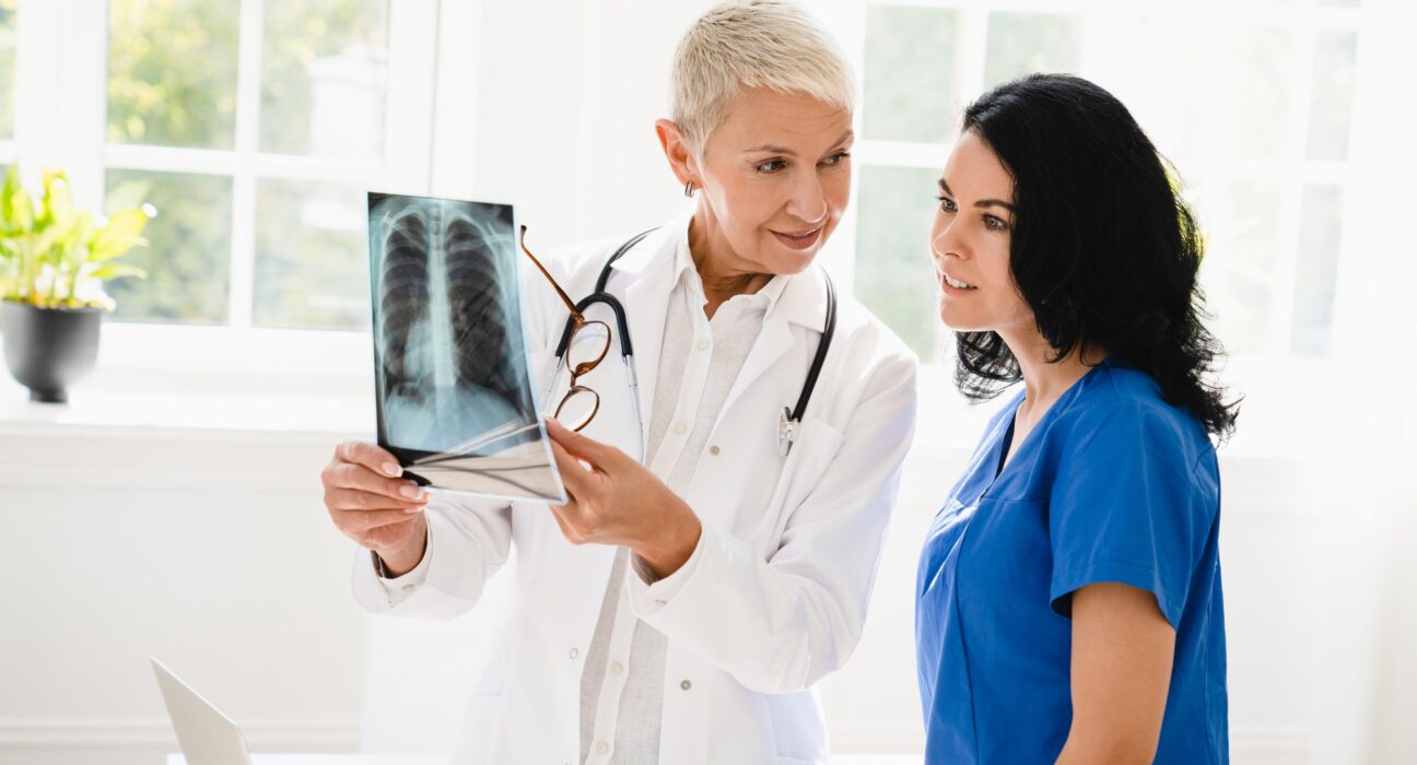 Doctor showing x-ray image of lungs to medical student intern nurse, explaining illness diagnosis