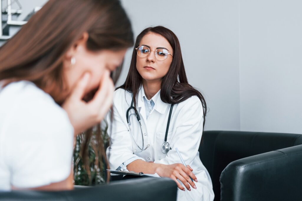 Girl have mental breakdown and crying. Young woman have a visit with female doctor in modern clinic