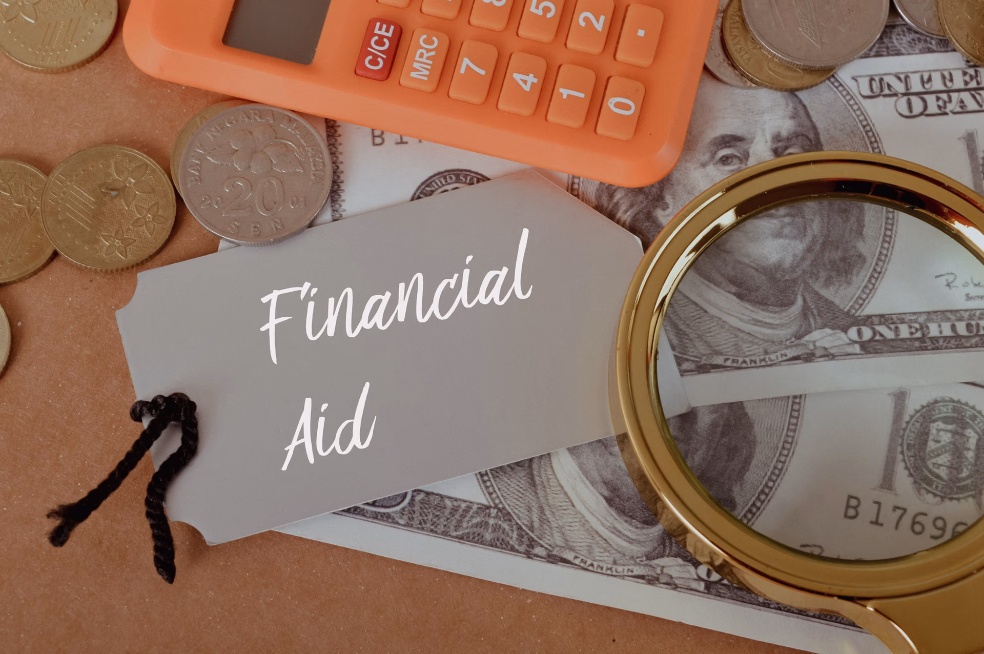 Magnifying glass, calculator and money with text FINANCIAL AID.