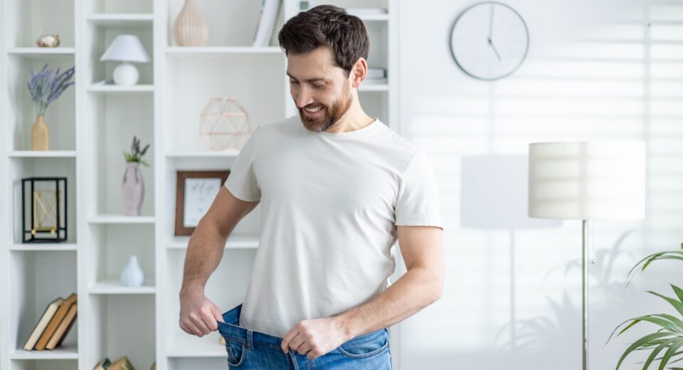 Man proudly showing weight loss in casual home setting