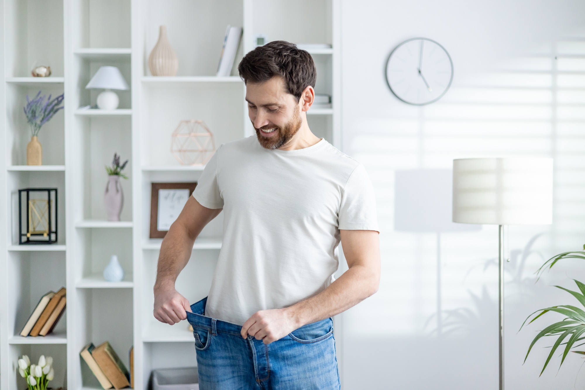 Man proudly showing weight loss in casual home setting