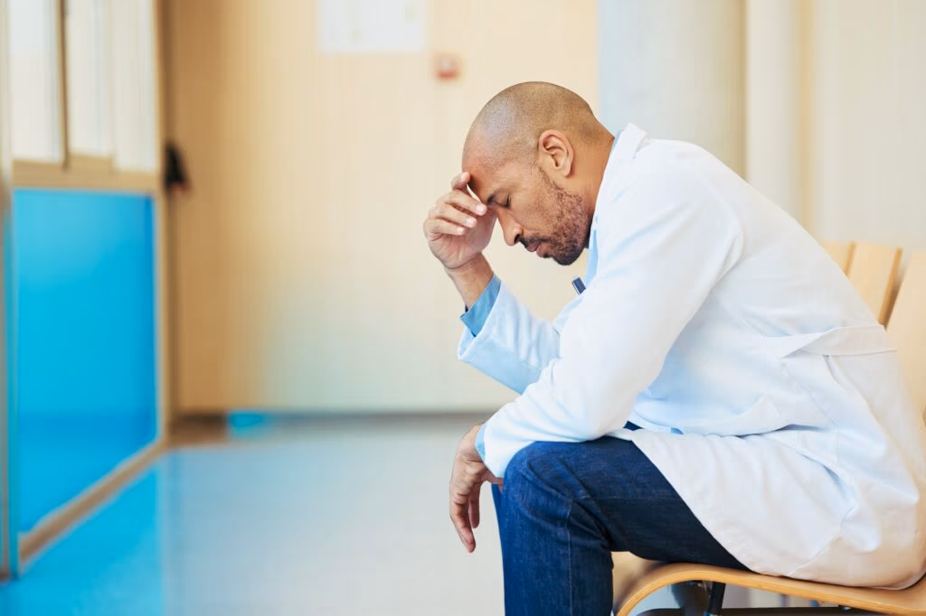 Overworked doctor suffering from stress and burnout in hospital corridor