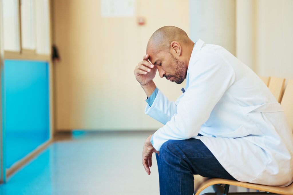 Overworked doctor suffering from stress and burnout in hospital corridor