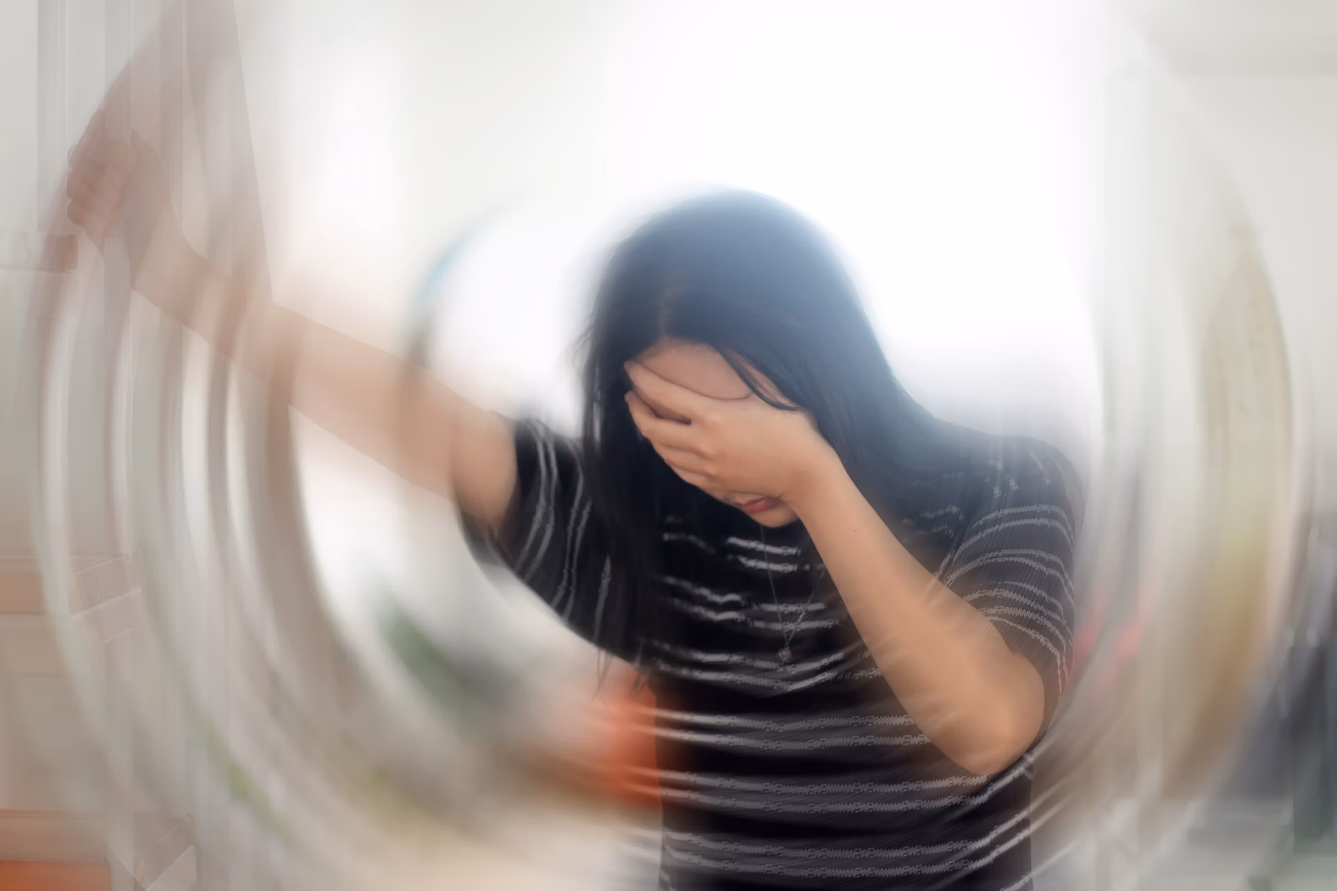 Portrait Of Young Woman Suffering From Vertigo Or Dizziness With Blurred