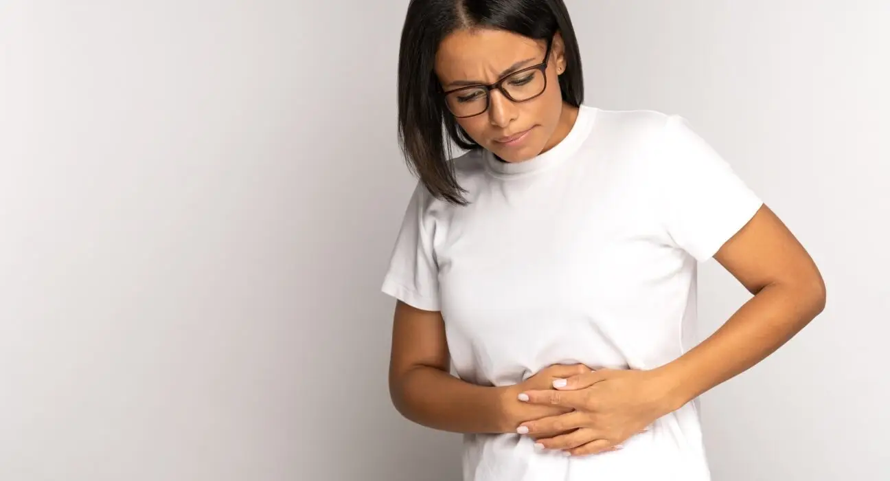 Sad African american woman in early pregnancy, suffer from stomachache pain touching belly with arms