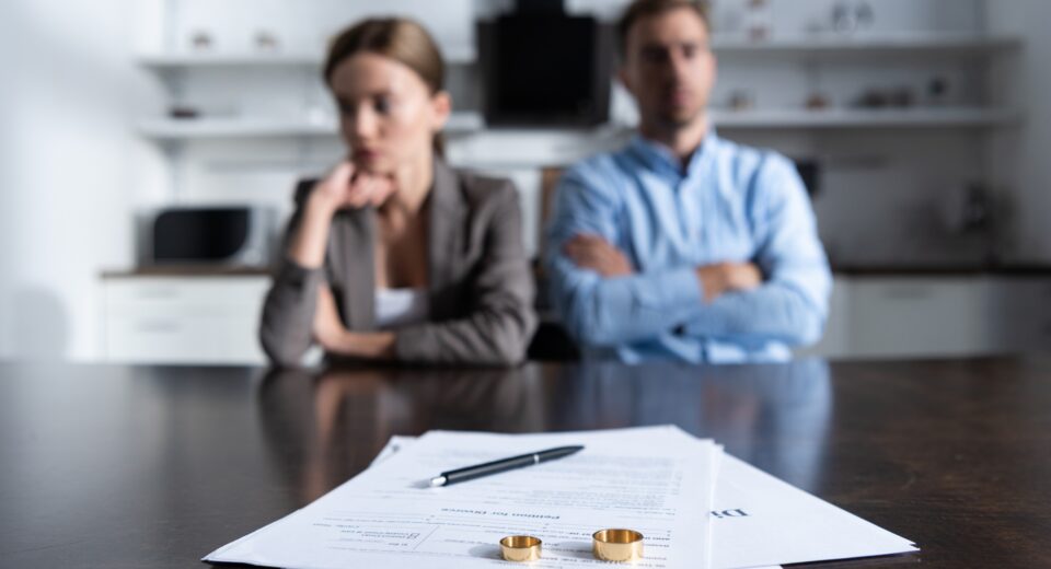 selective focus of couple sitting at table with divorce documents