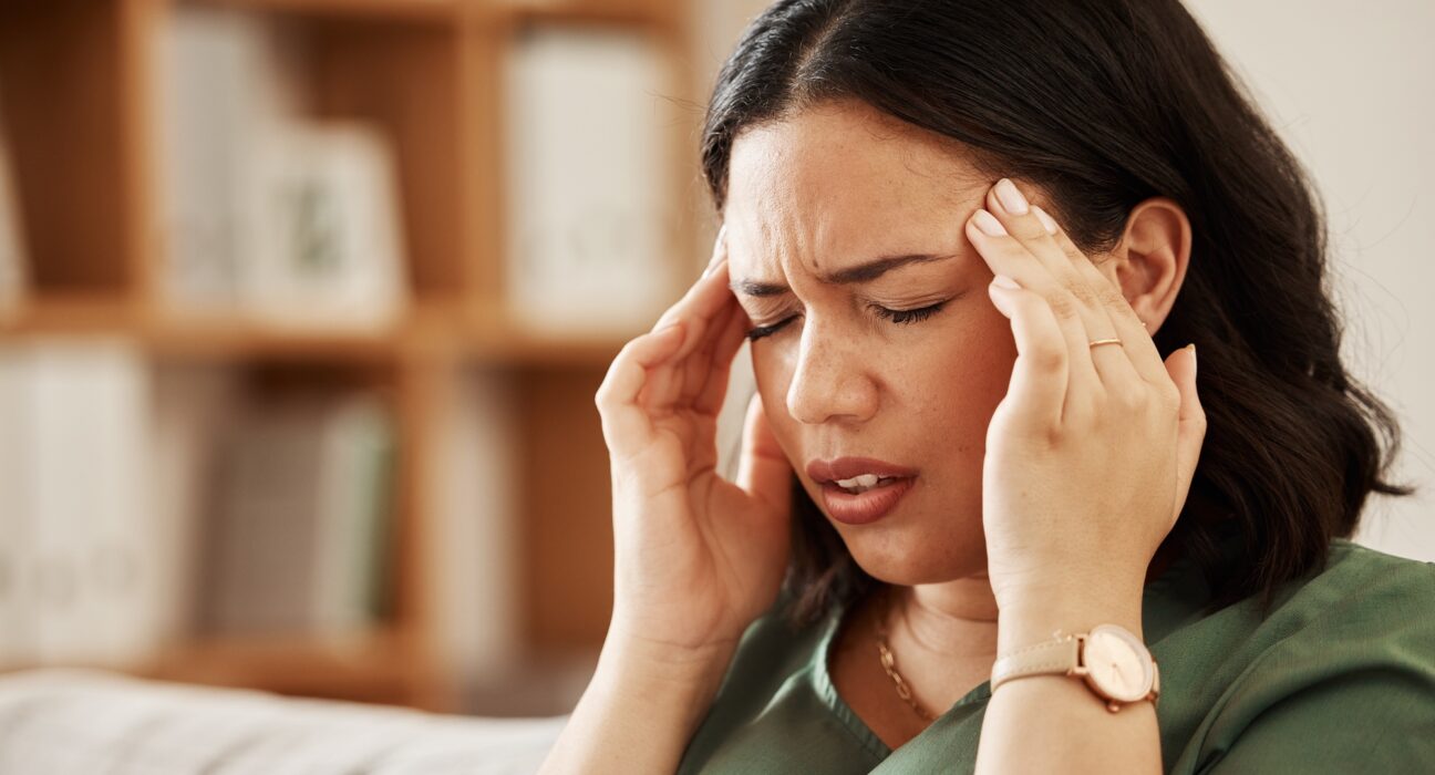 Stress, headache and woman on a sofa with vertigo, brain fog or burnout in her home. Migraine, anxi