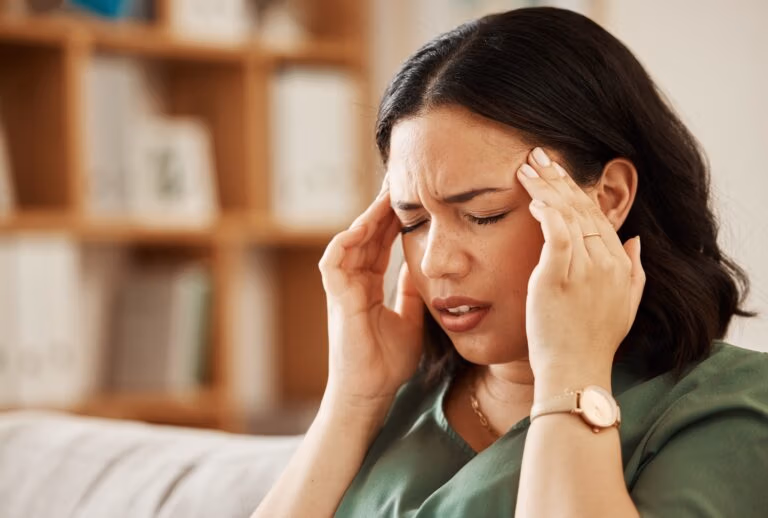 Stress, headache and woman on a sofa with vertigo, brain fog or burnout in her home. Migraine, anxi