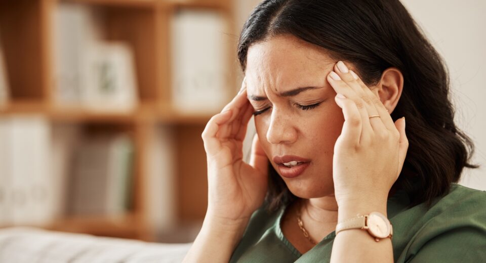 Stress, headache and woman on a sofa with vertigo, brain fog or burnout in her home. Migraine, anxi
