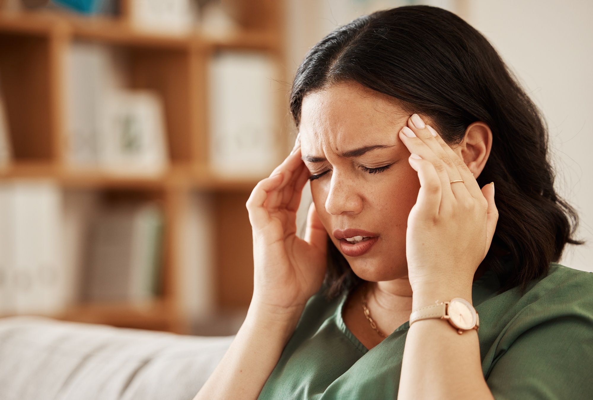 Stress, headache and woman on a sofa with vertigo, brain fog or burnout in her home. Migraine, anxi