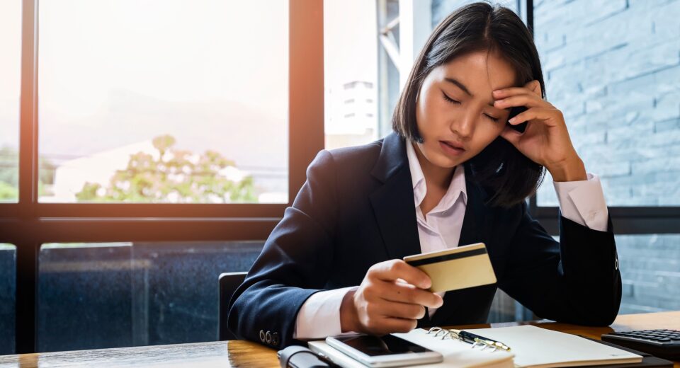 Stressful asian businesswoman with huge amount of credit card debt
