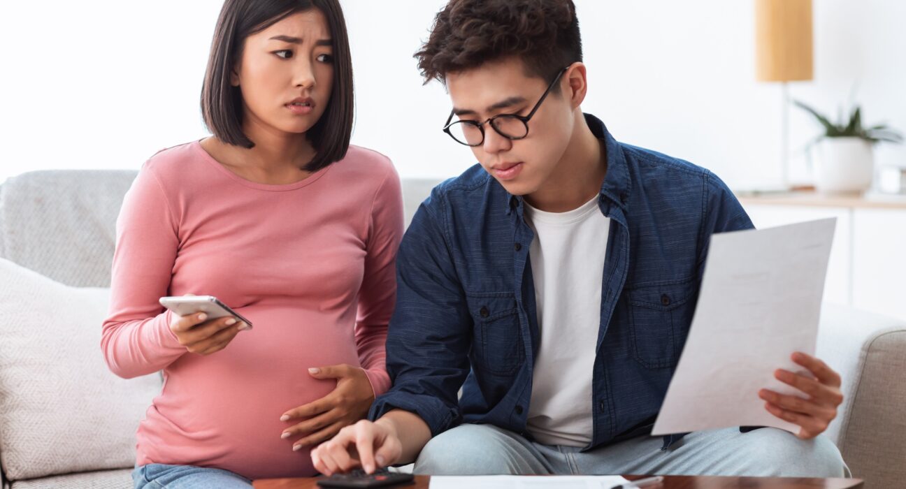 Unhappy Chinese Spouses Calculating Bills Sitting On Sofa At Home