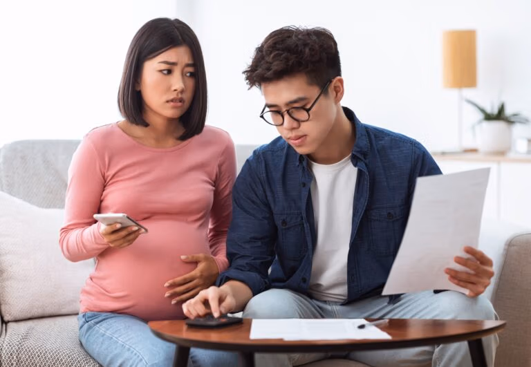 Unhappy Chinese Spouses Calculating Bills Sitting On Sofa At Home
