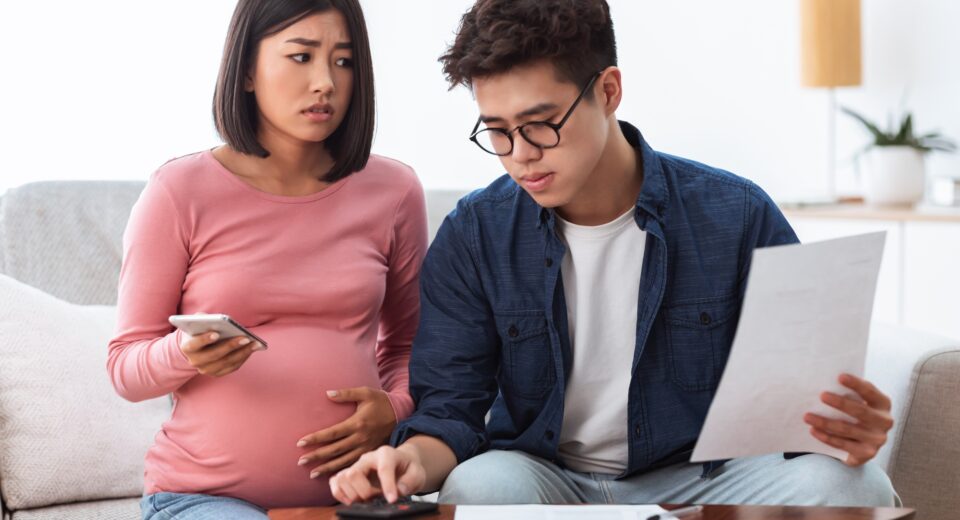 Unhappy Chinese Spouses Calculating Bills Sitting On Sofa At Home