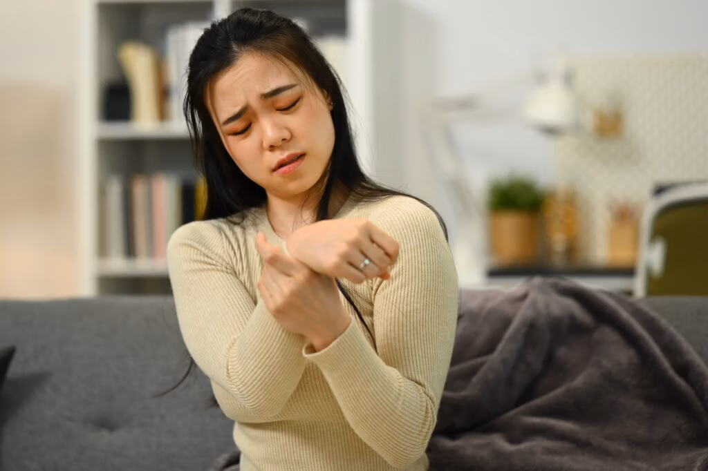 Unhappy woman suffering from pain in hand or wrist, having osteoarthritis rheumatoid arthritis.