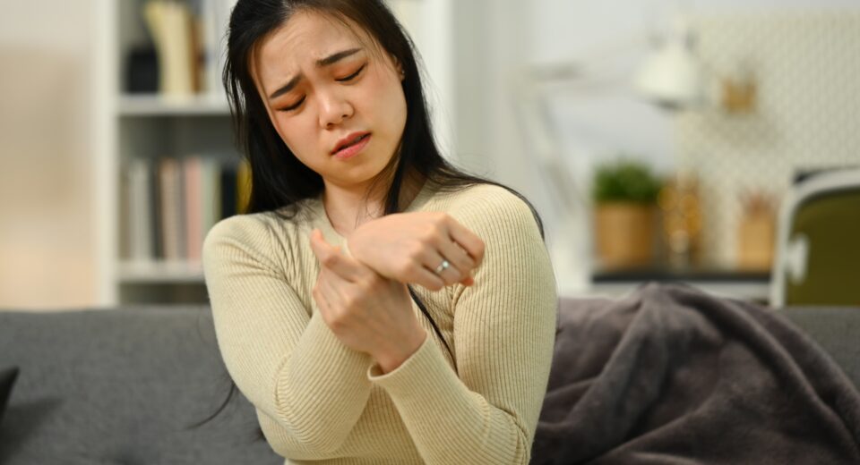Unhappy woman suffering from pain in hand or wrist, having osteoarthritis rheumatoid arthritis.