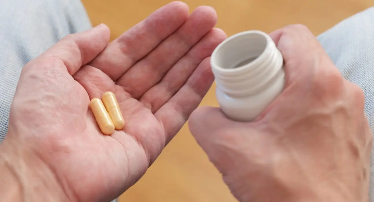 A man poured vitamin B complex pills from a plastic bottle into his palm