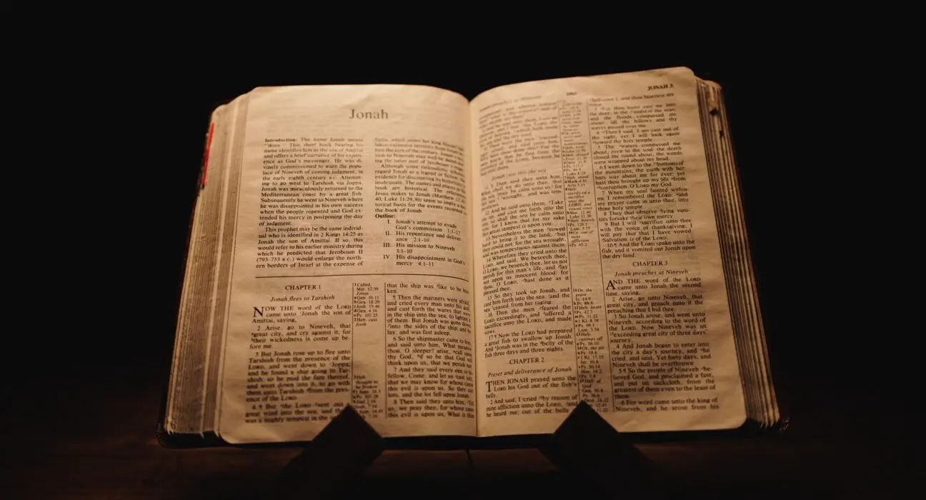 Closeup shot of a historic old Bible open on the Jonah pages on display in a dark room