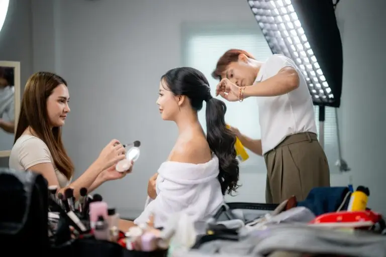 Makeup artist and hairdresser preparing beautiful model for photo shooting