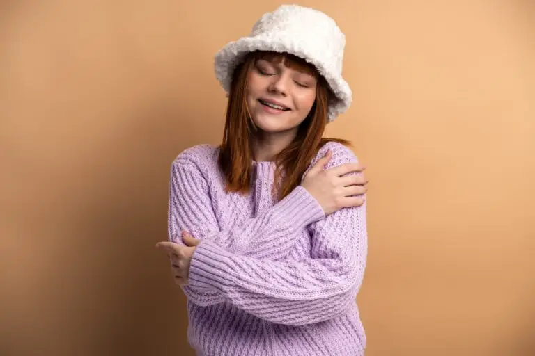 Pleased satisfied ginger girl hugging herself and smiling, feeling comfortable and fulfilled