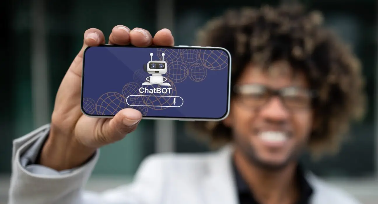 Positive african american entrepreneur showing phone with chatbot
