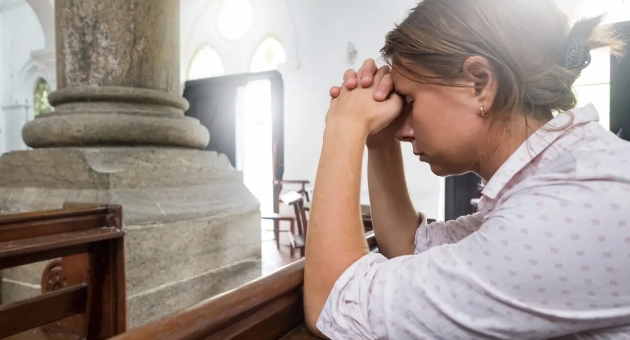 Praying woman in christian church praying God for help.