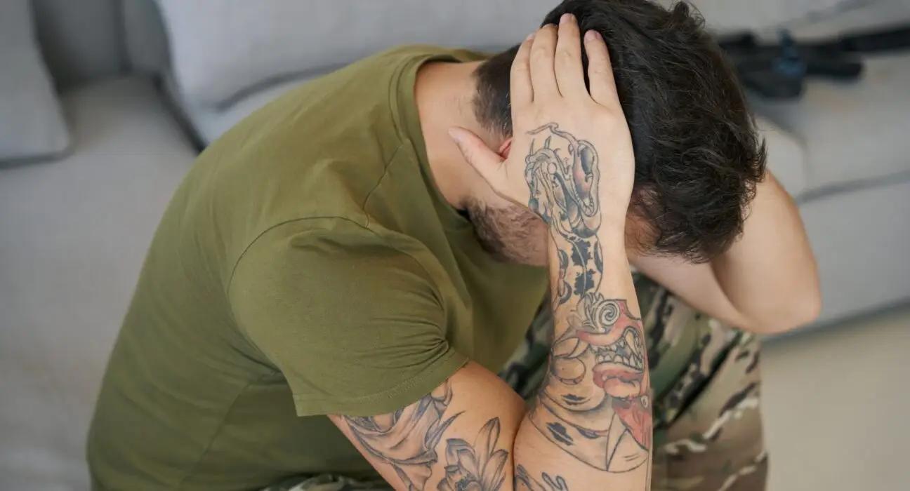Serviceman grabbing head with hands while suffering from PTSD