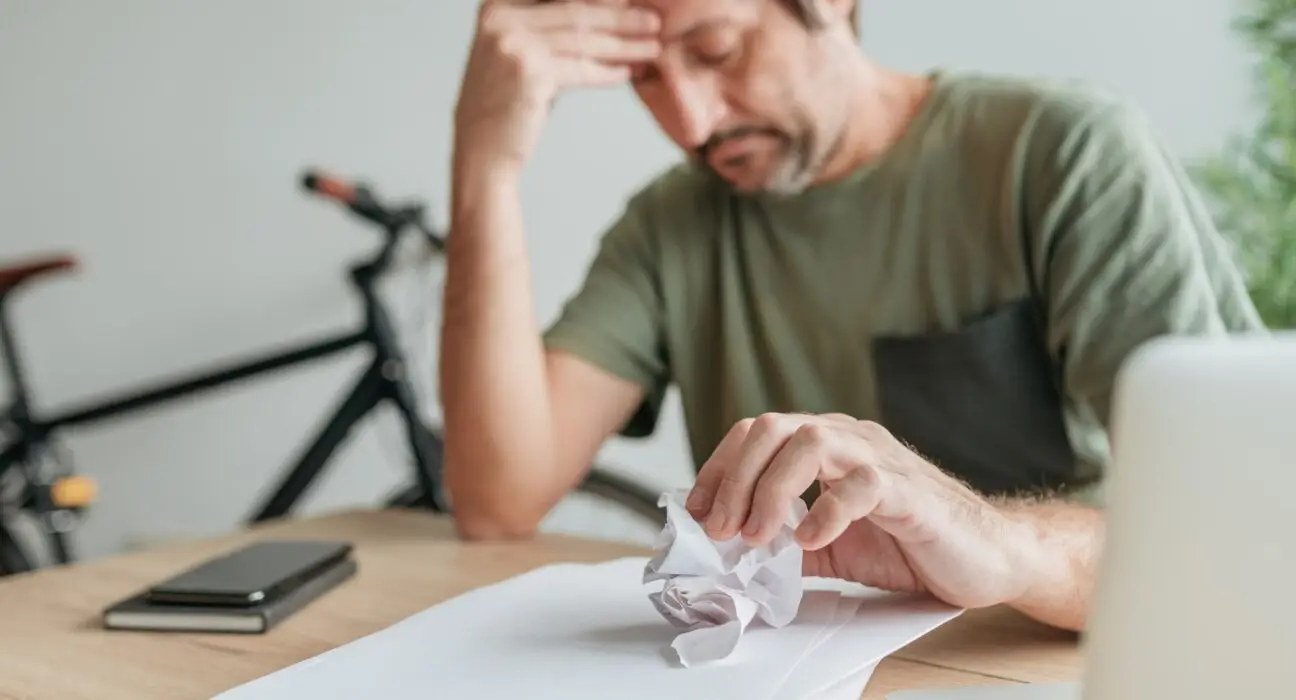Telecommuter with creative block in home office crumpling sheet of paper