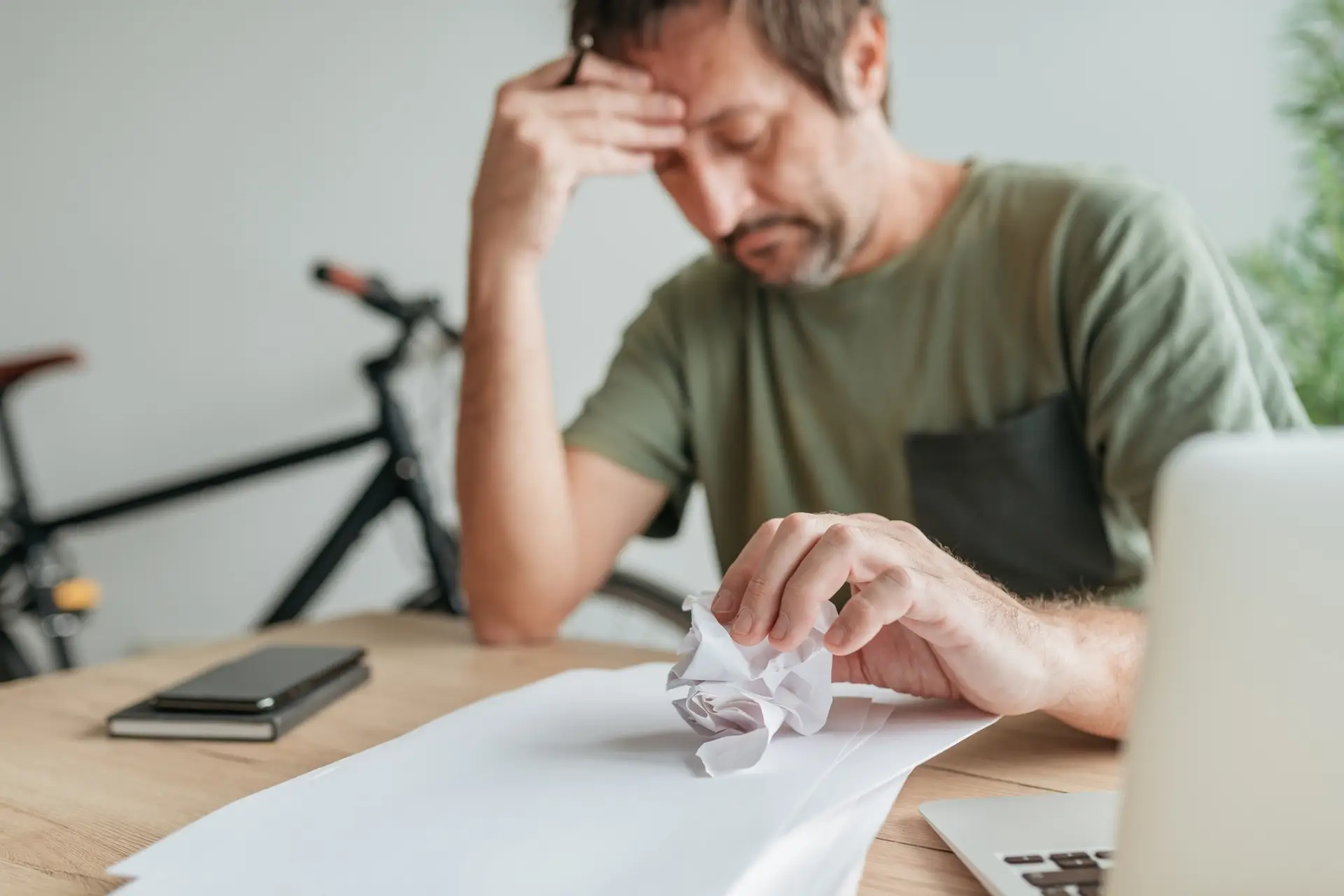 Telecommuter with creative block in home office crumpling sheet of paper