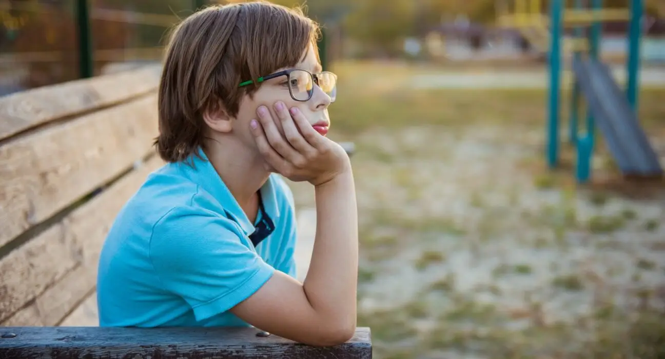 Upset kid problem sitting on play park playground bench. Concept bullying, depression