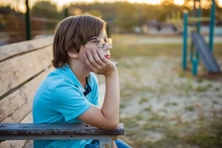 Upset kid problem sitting on play park playground bench. Concept bullying, depression