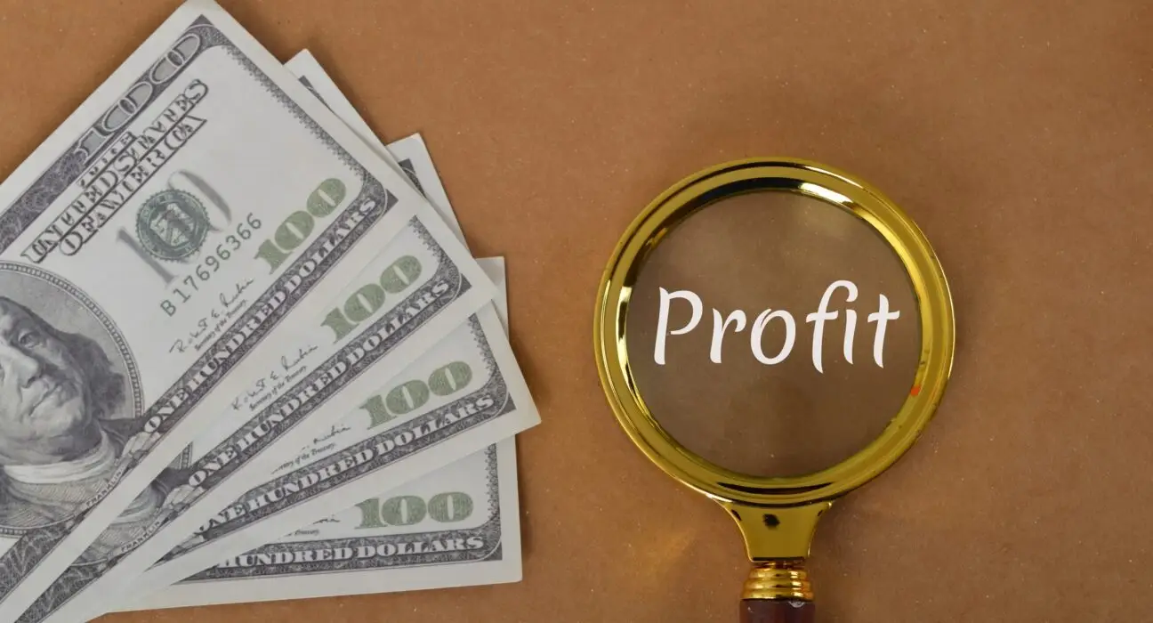 Money banknotes and magnifying glass with text PROFIT.
