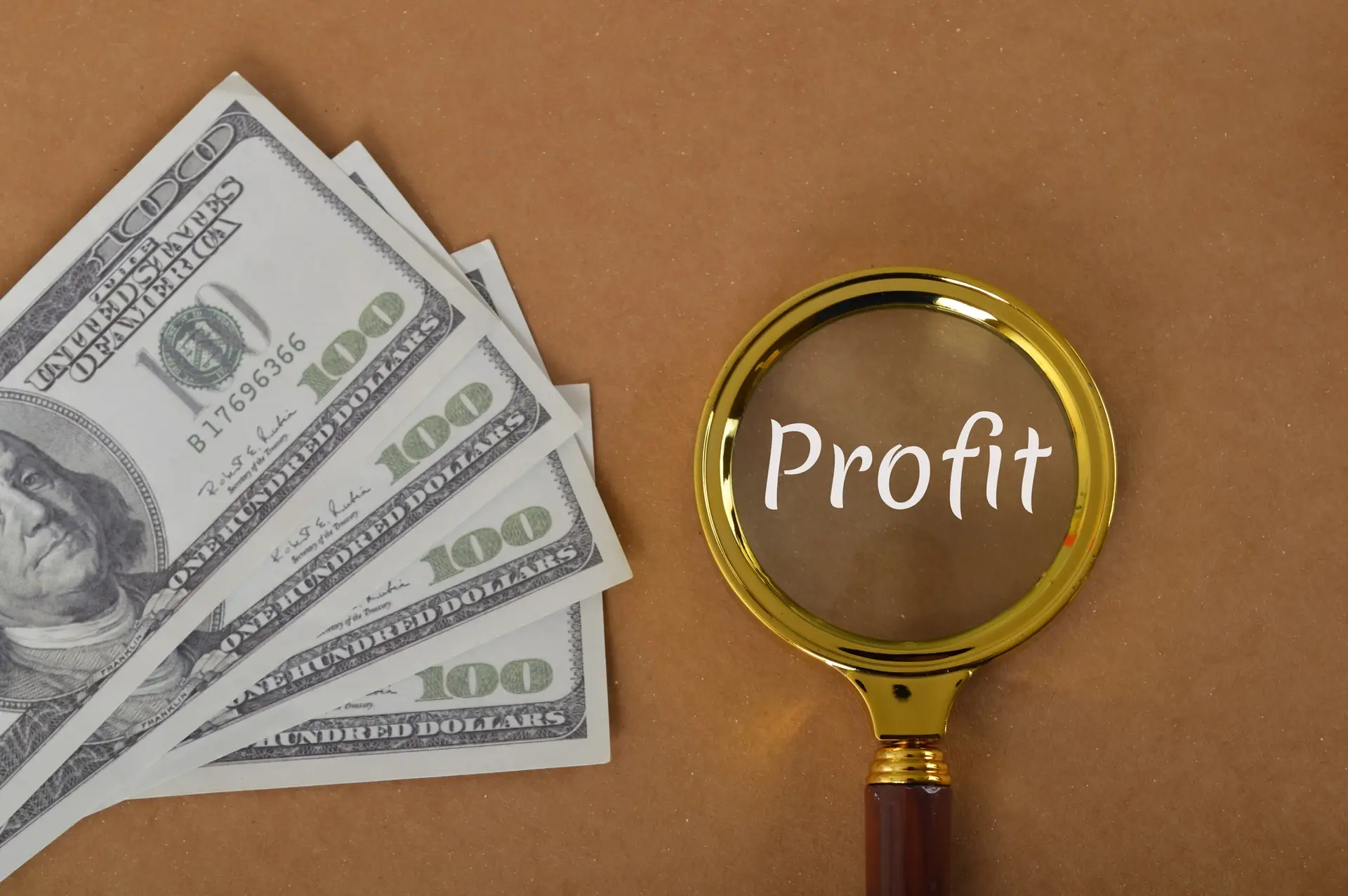 Money banknotes and magnifying glass with text PROFIT.
